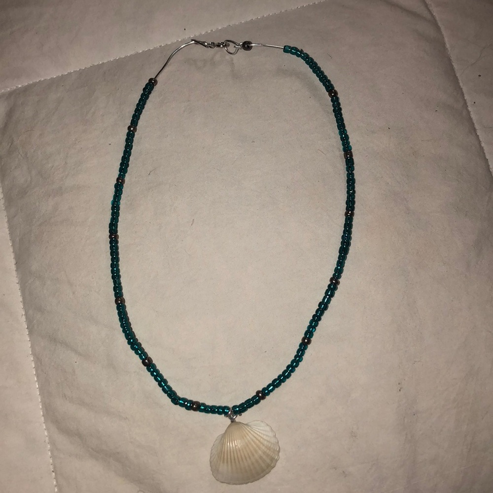 A blue and silver necklace with a shell.